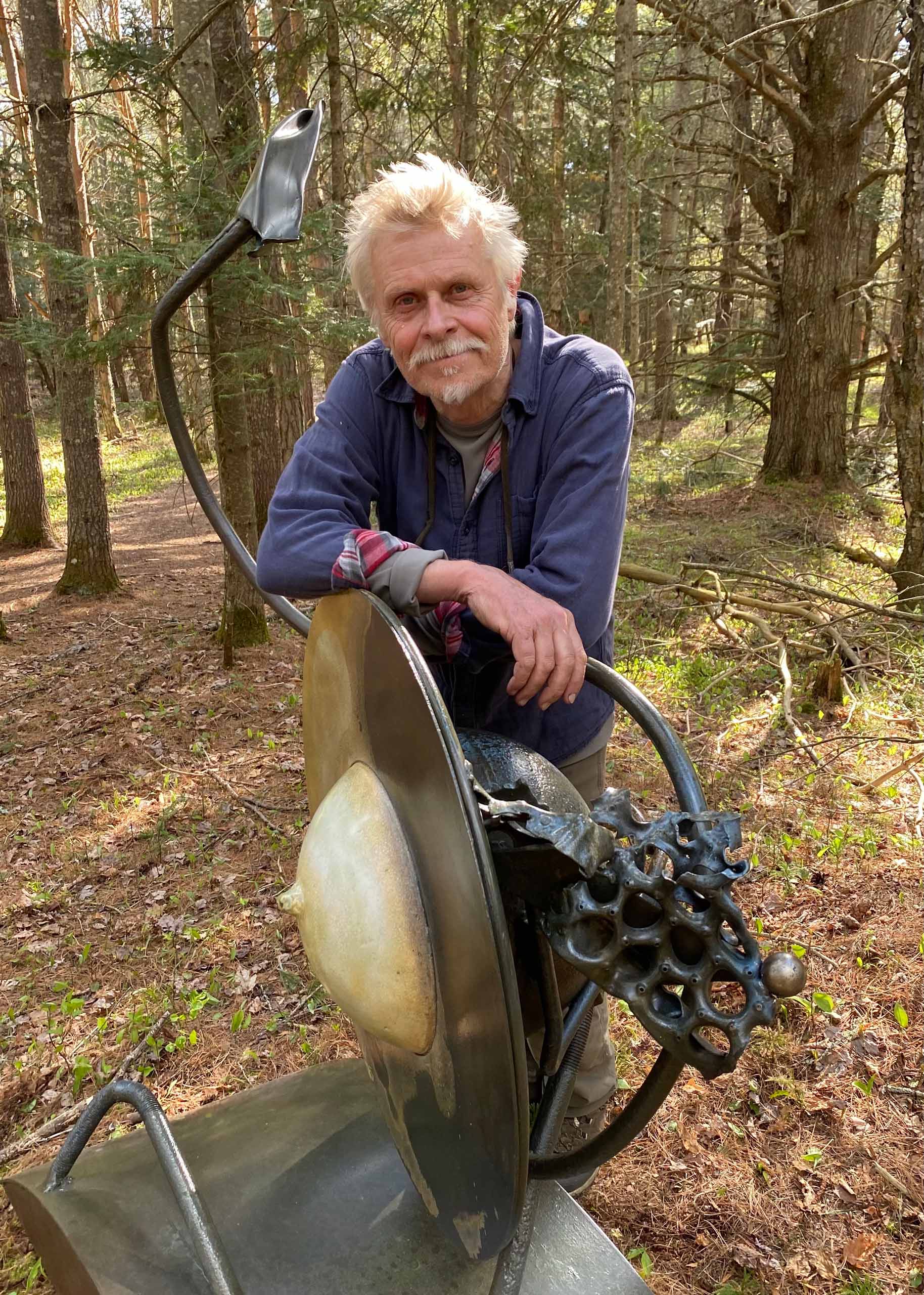 Barney Bellinger posing with one of his pieces in the forest