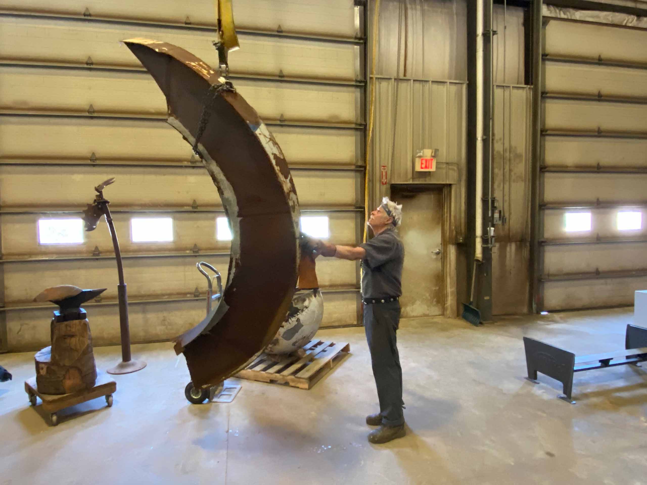 Barney Bellinger inspecting a large piece of an installation in his workshop