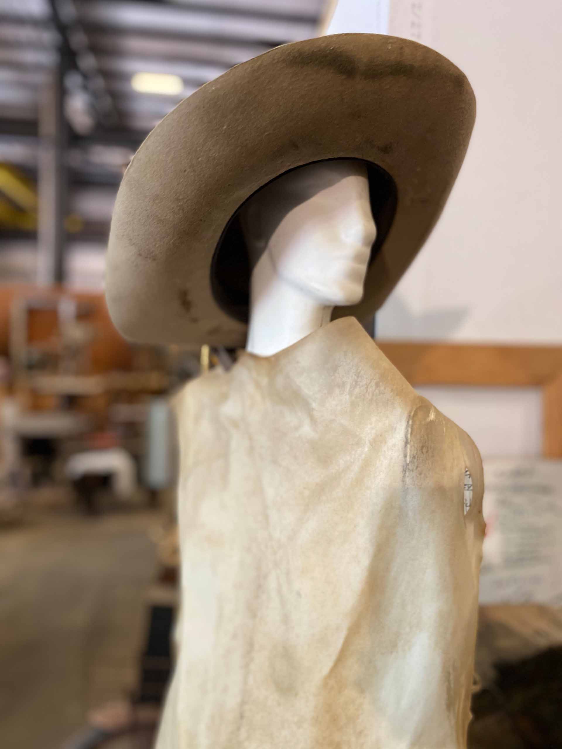 Closeup of mannequin wearing hat and smock in Barney Bellinger’s workshop