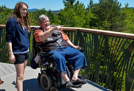 Man in wheelchair pointing out view to accompanying child