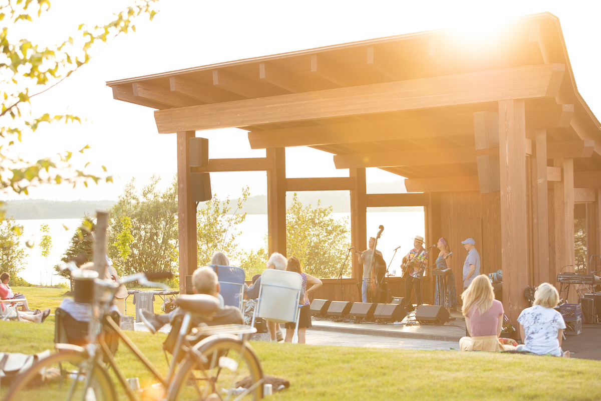 People watching performance in park from band under outdoor structure