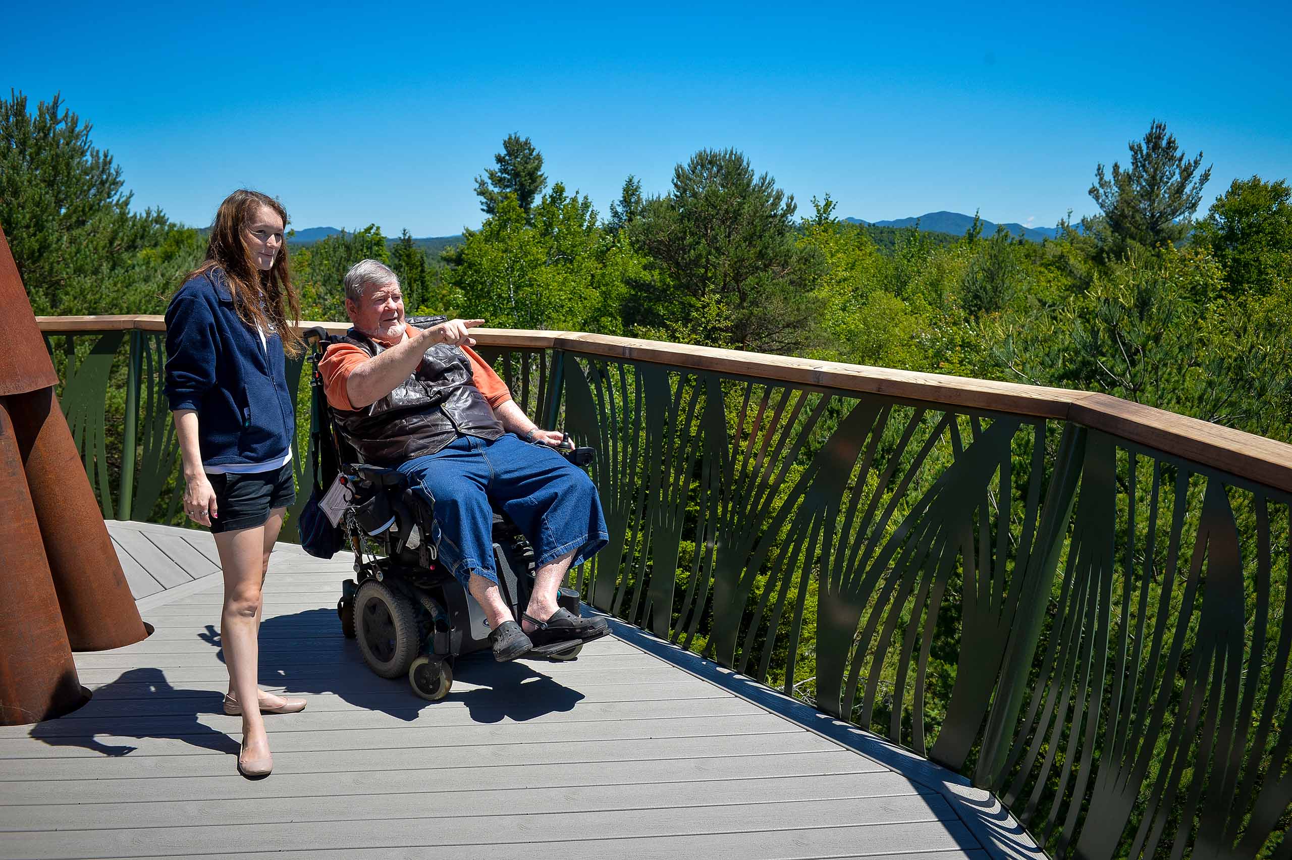 Wild Center visitor in wheelchair on Wild Walk points out detail to teenage girl.