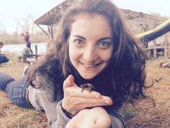 Woman laying on ground with small turtle in hand
