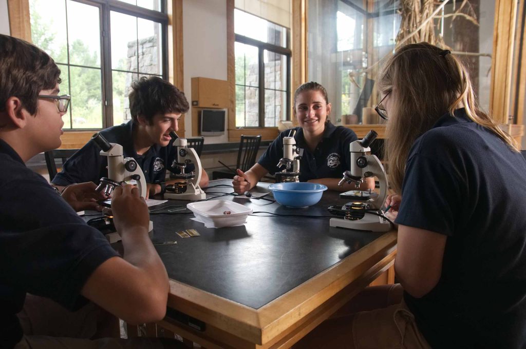 Group of students at table examining items through microscrope