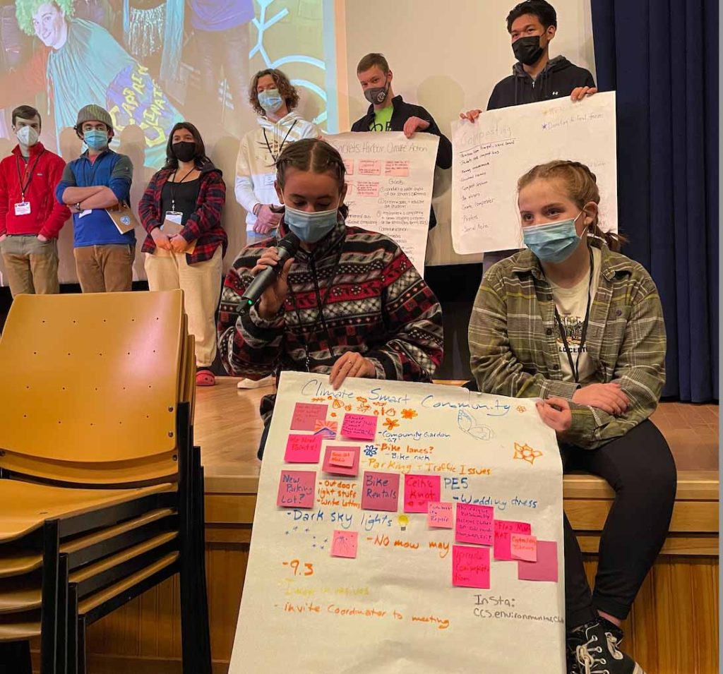 Students on stage explaining their climate change poster display