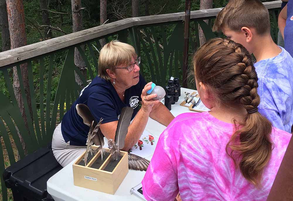 Woman demonstrating exhibit to Wild Center guests