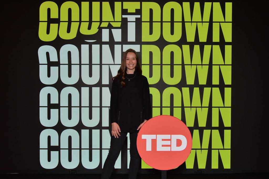 Elodie posing in front of Ted signage