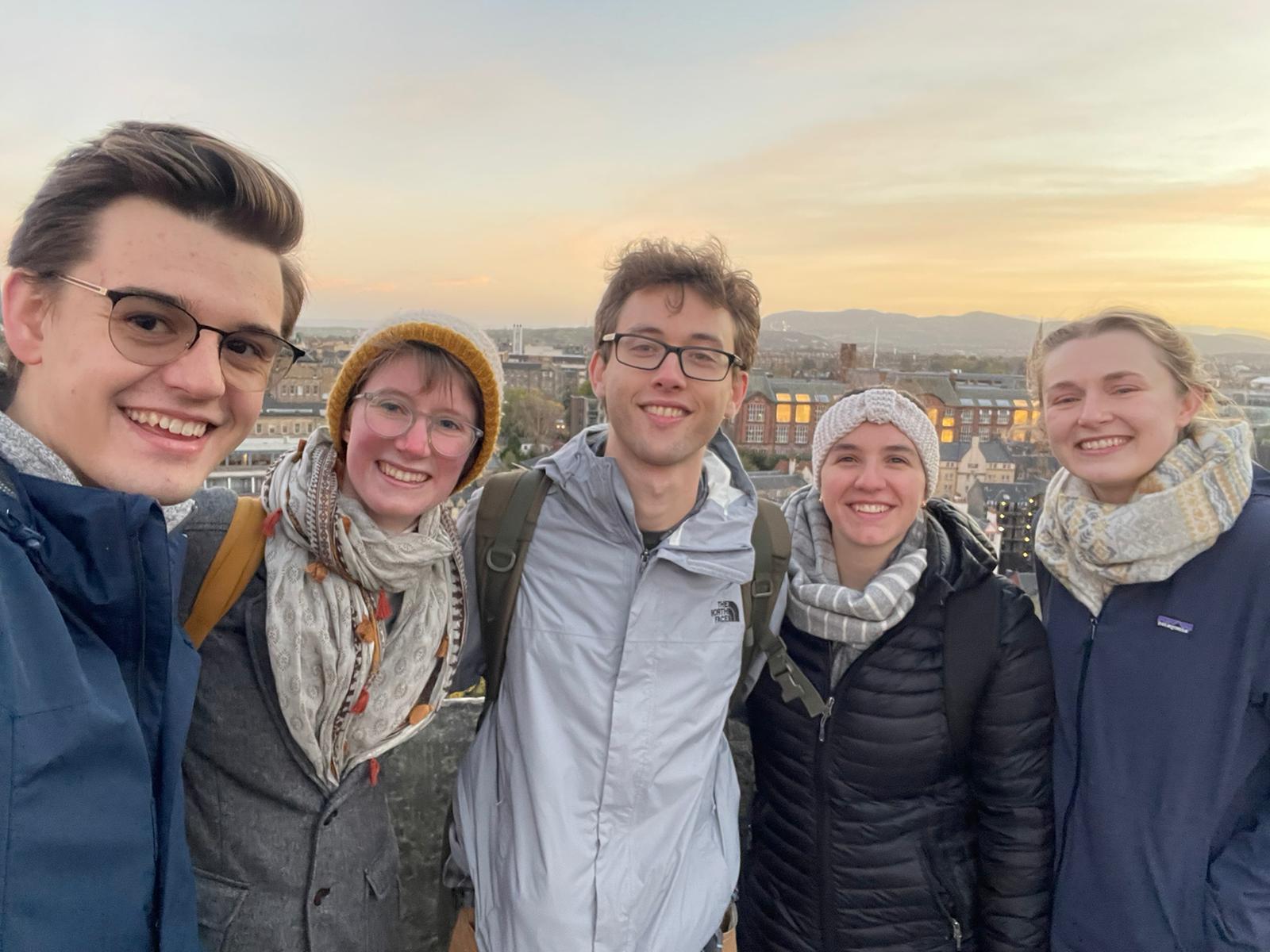 Group smiling posing for photo with Edinburgh skyline in background